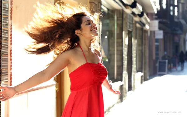 HD desktop wallpaper featuring Raashi Khanna, a woman in a flowing red dress, smiling with arms outstretched on a sunny street.