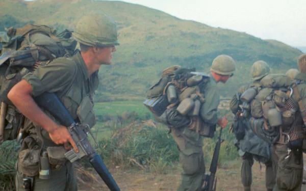 Vietnam War military scene: soldiers in helmets and heavy packs advancing through grassy hills, 4K Ultra HD PC desktop wallpaper/background.