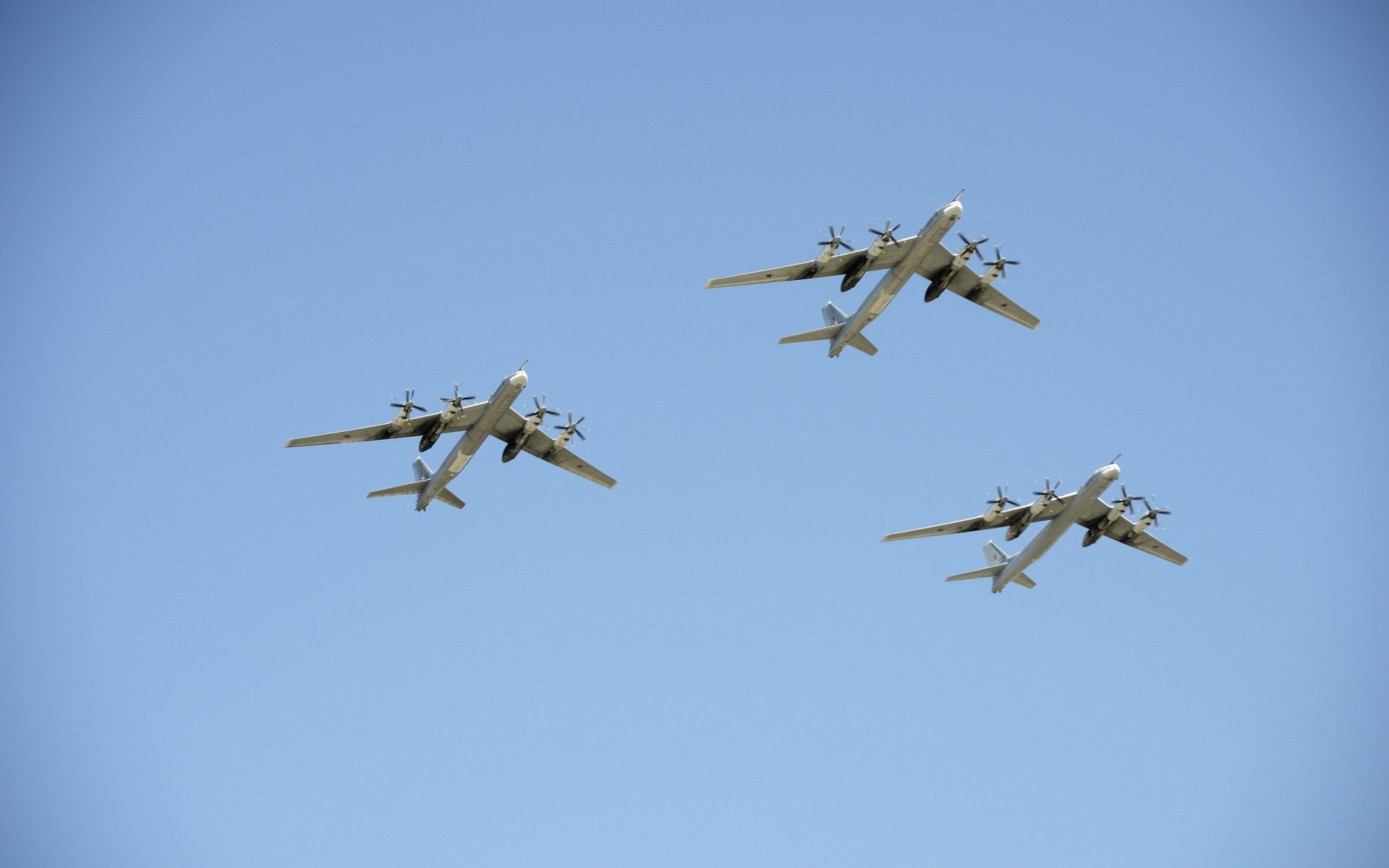 HD desktop wallpaper featuring three Tupolev Tu-95 military bombers flying in formation against a clear blue sky.
