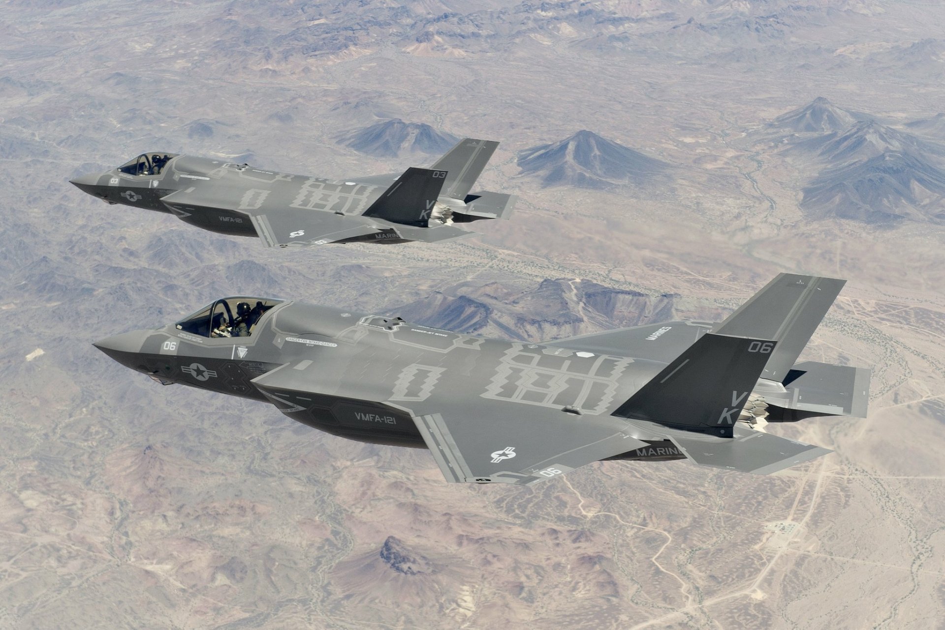 Two Lockheed Martin F-35 Lightning II fighter jets flying over a desert landscape in this HD military-themed PC desktop wallpaper.