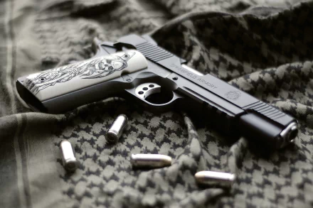 HD desktop wallpaper featuring a Springfield Armory pistol with detailed grips, resting on patterned fabric alongside scattered bullets.