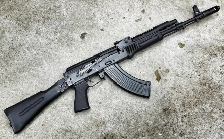 HD desktop wallpaper image of a man-made AK 47 rifle placed on a textured concrete surface.