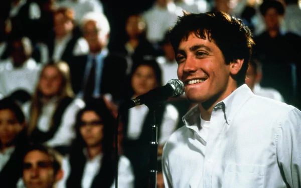 HD desktop wallpaper featuring Jake Gyllenhaal as Donnie Darko, smiling at a microphone in front of a crowd.