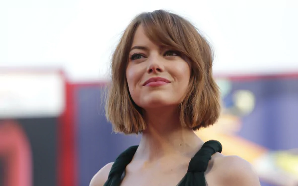 4K Ultra HD wallpaper featuring Emma Stone at a film event, with her smiling and looking confidently at the camera. A vibrant background enhances the celebrity's presence.