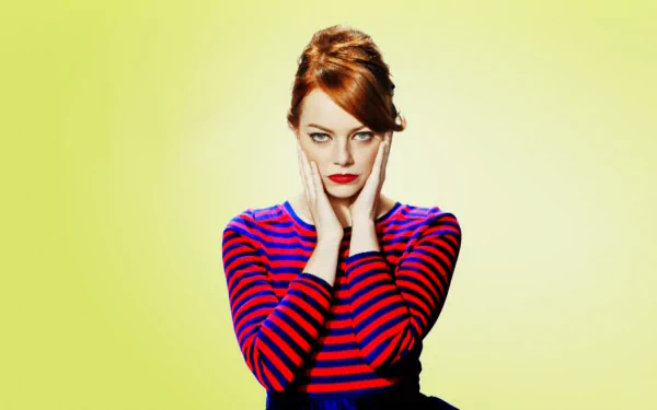 Emma Stone poses thoughtfully against a soft yellow background, wearing a striped shirt. This vibrant HD image serves as a stylish desktop wallpaper.