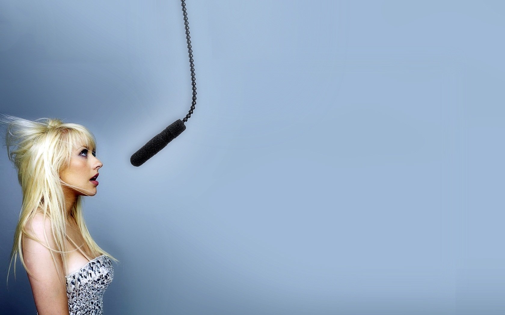 HD PC desktop wallpaper featuring Christina Aguilera singing toward a suspended microphone against a soft blue background, highlighting music and vocal performance.
