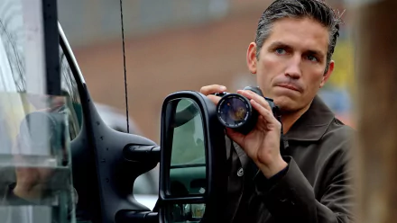 HD PC desktop wallpaper featuring a scene from the TV show Person of Interest, depicting a man intently holding a camera lens by a vehicle.