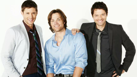 A high-definition wallpaper featuring Jensen Ackles, Jared Padalecki, and Misha Collins, stars of the TV show Supernatural, posing together with smiles.