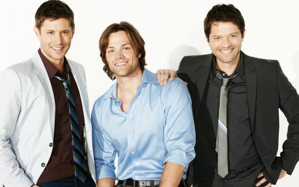 A high-definition wallpaper featuring Jensen Ackles, Jared Padalecki, and Misha Collins, stars of the TV show Supernatural, posing together with smiles.