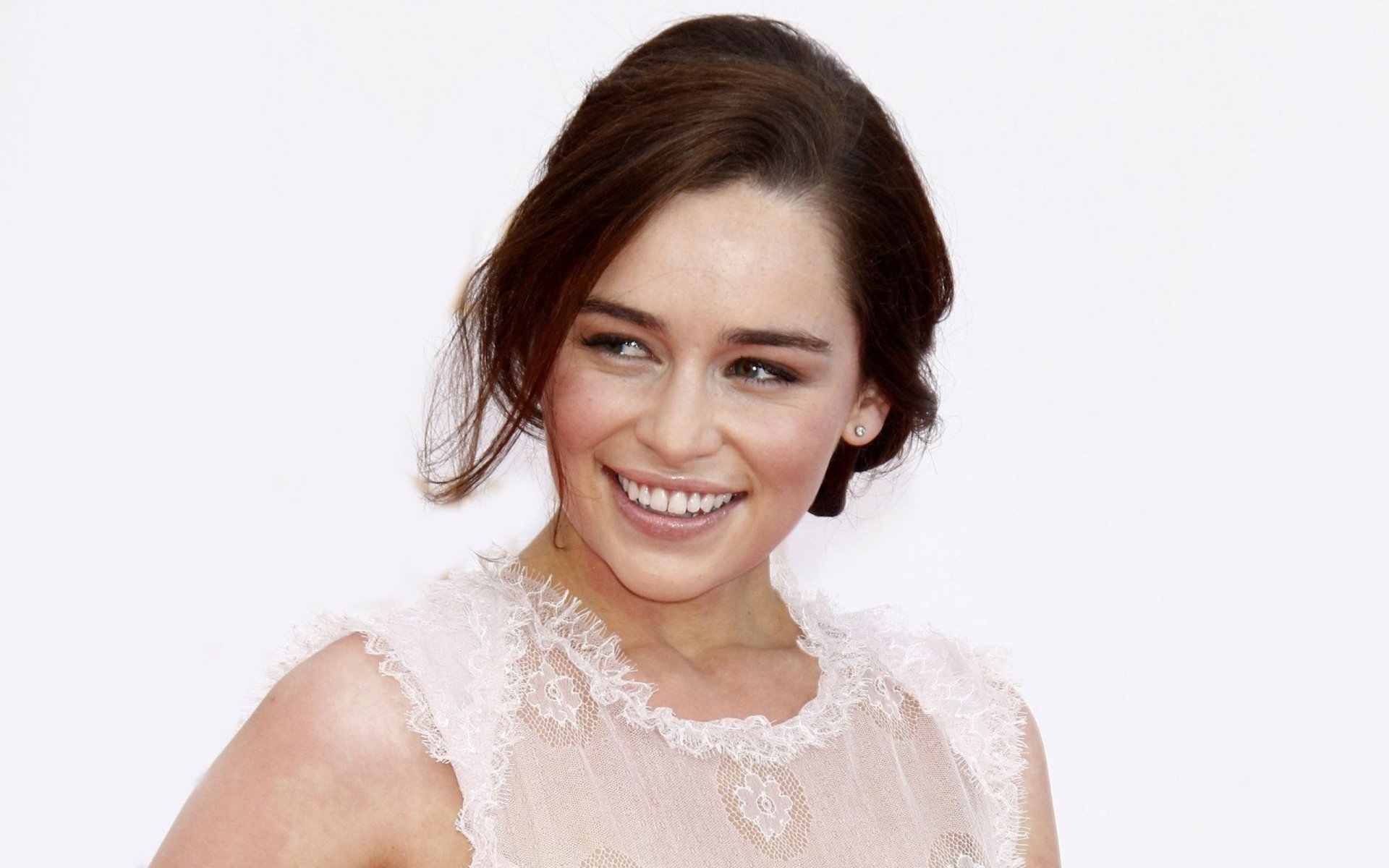 Emilia Clarke smiles gracefully in a delicate, light-colored dress, captured in a vibrant HD wallpaper for PC desktop backgrounds.