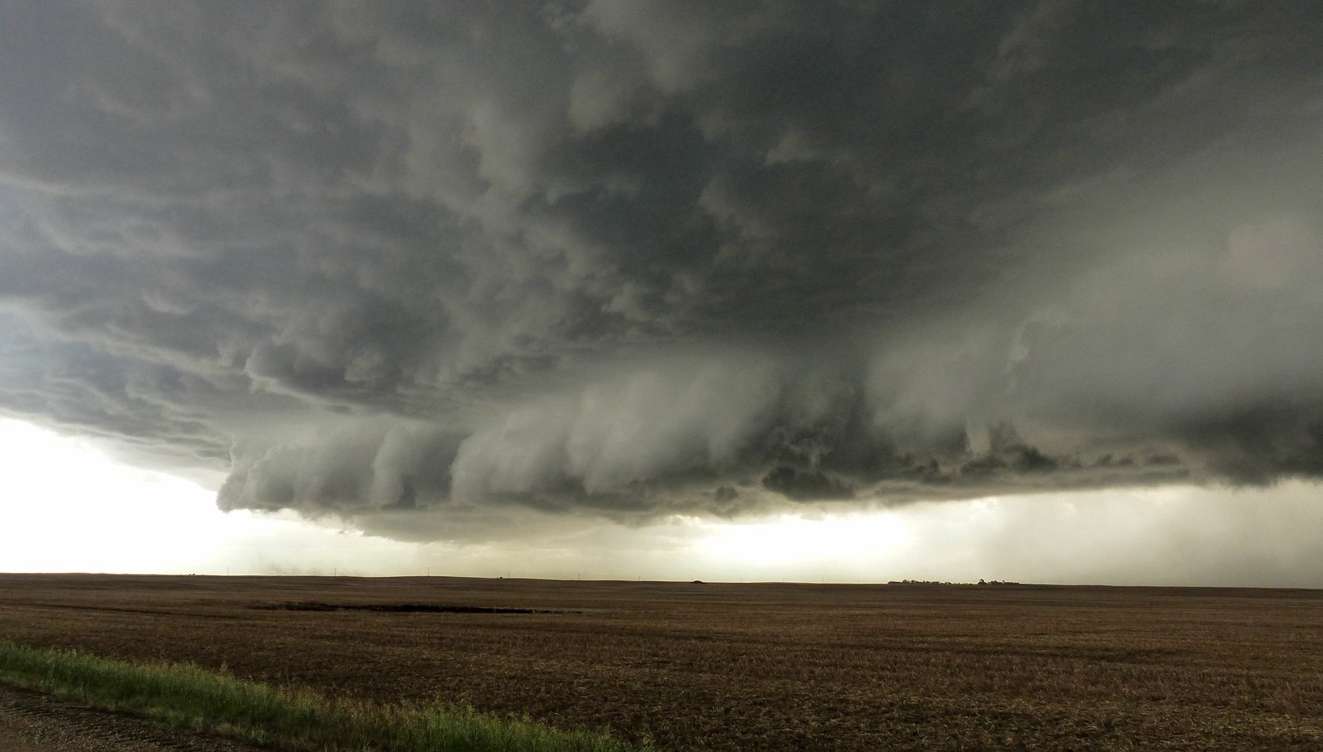 4K Ultra HD desktop wallpaper capturing a dramatic storm rolling over a vast open field under dark, swirling clouds in nature.