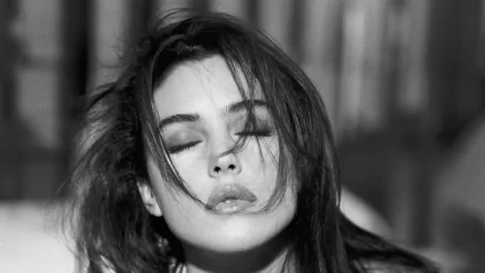 Black and white portrait of celebrity Monica Bellucci, with her eyes closed and tousled hair, creating a captivating and emotive atmosphere. High-definition wallpaper for desktop use.
