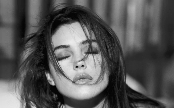 Black and white portrait of celebrity Monica Bellucci, with her eyes closed and tousled hair, creating a captivating and emotive atmosphere. High-definition wallpaper for desktop use.