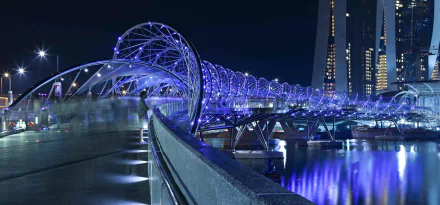 Night view of The Helix Bridge in Singapore, a man-made double-helix pedestrian bridge glowing blue over reflective water — 5K Ultra HD PC desktop wallpaper.