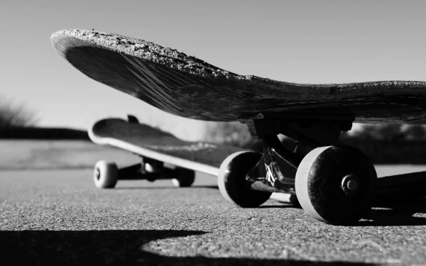 Black and white 4K Ultra HD desktop wallpaper featuring a close-up of two skateboards on pavement, capturing the essence of skateboarding and sports.