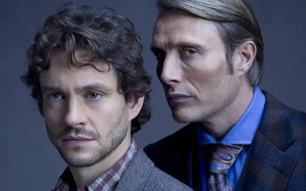 2K Quad HD desktop wallpaper for the TV show Hannibal: two men in formal attire posed closely in a moody blue studio portrait.