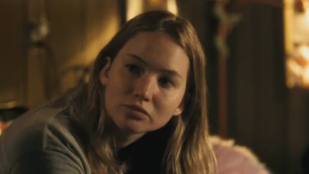 HD desktop wallpaper featuring Jennifer Lawrence in a scene from the movie Winter's Bone, showcasing her contemplative expression in a dimly lit setting.