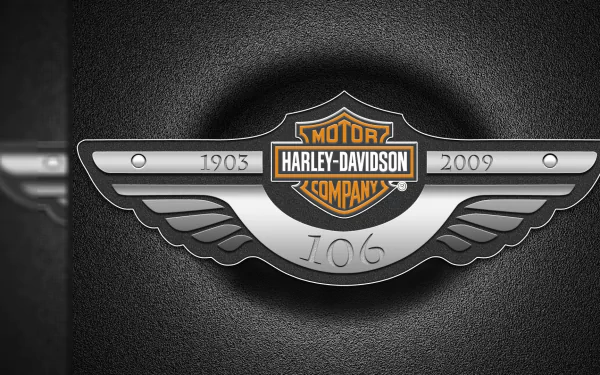 Harley-Davidson logo displayed on a sleek metallic emblem with wing details, set against a textured background in this HD PC desktop wallpaper.