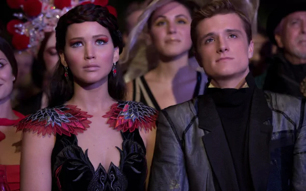 A stunning HD wallpaper featuring Josh Hutcherson and Jennifer Lawrence in a scene from *The Hunger Games: Catching Fire*, capturing their intense expressions amidst a vibrant backdrop.