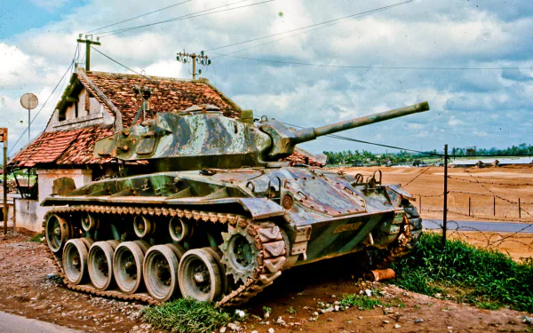 HD desktop wallpaper featuring an M24 Chaffee tank from the Vietnam War, set against a rural military backdrop with blue skies and scattered clouds.