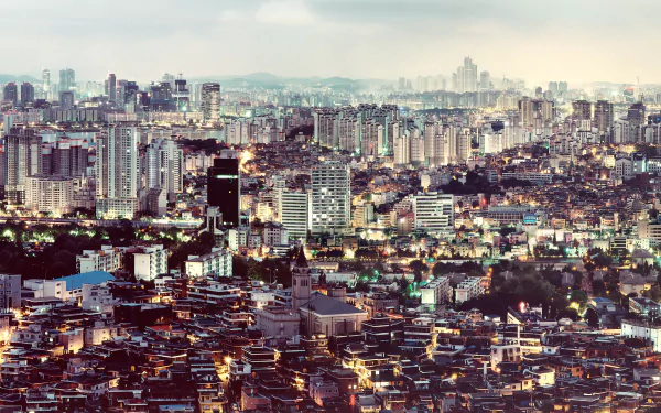 HD desktop wallpaper of Seoul's cityscape, showcasing a mix of modern skyscrapers and traditional buildings under a cloudy sky.