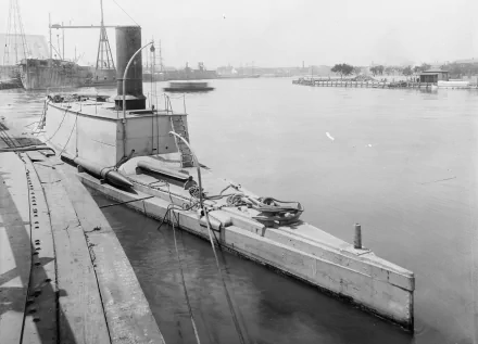 Black-and-white 4K Ultra HD PC desktop wallpaper of a military torpedo boat moored in a calm harbor with industrial piers and distant ships.