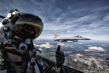 A pilot gives a thumbs-up from the cockpit of a military aircraft, with a General Dynamics F-16 Fighting Falcon flying alongside against a dramatic sky. HD wallpaper background.