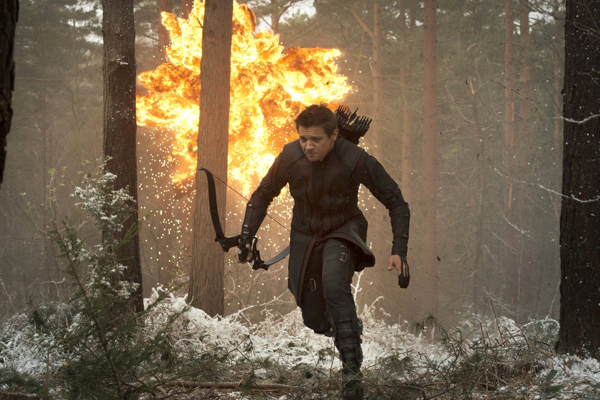 Hawkeye, portrayed by Jeremy Renner, charges through a fiery forest in this striking 4K Ultra HD desktop wallpaper from *Avengers: Age of Ultron*.