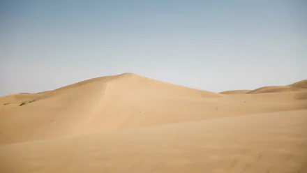 4K Ultra HD PC desktop wallpaper: sweeping sand dunes of the Arabian Desert under a pale blue sky, minimalist nature scene of golden desert sand.