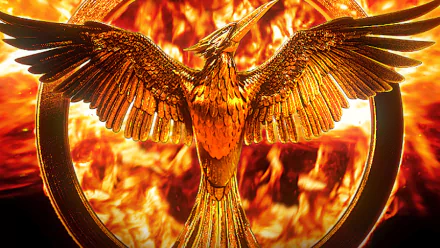 5K Ultra HD PC desktop wallpaper — movie The Hunger Games: Mockingjay - Part 2; golden Mockingjay emblem with outstretched wings amid roaring flames.