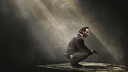 HD desktop wallpaper featuring Rick Grimes, portrayed by Andrew Lincoln from the TV show The Walking Dead, kneeling in a spotlight in a dark, moody atmosphere.