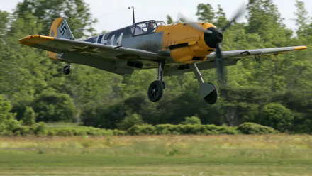 A Messerschmitt Bf 109 aircraft gracefully flies above a lush green landscape, showcasing its military design in this high-definition PC desktop wallpaper.