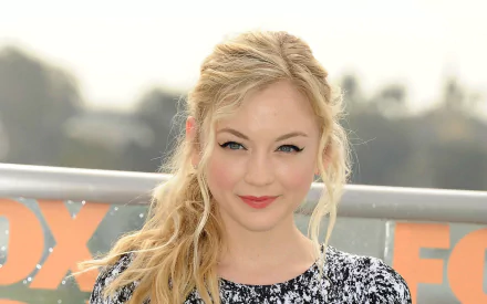 HD desktop wallpaper featuring American singer and actress Emily Kinney smiling outdoors with soft natural lighting.