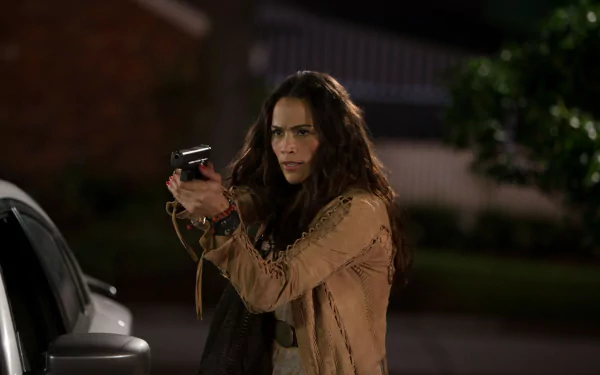Deb from the movie 2 Guns, played by Paula Patton, is shown aiming a handgun in a tense nighttime scene.