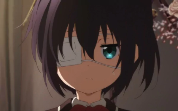 A close-up of Rikka Takanashi from Love, Chunibyo & Other Delusions, featuring her signature eye patch and expressive gaze, set against a softly blurred background.
