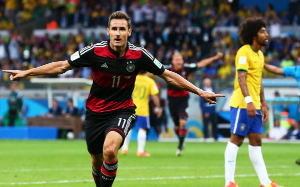 HD PC desktop wallpaper featuring an intense soccer match moment with a German player celebrating a goal, surrounded by Brazilian opponents in a vibrant stadium.