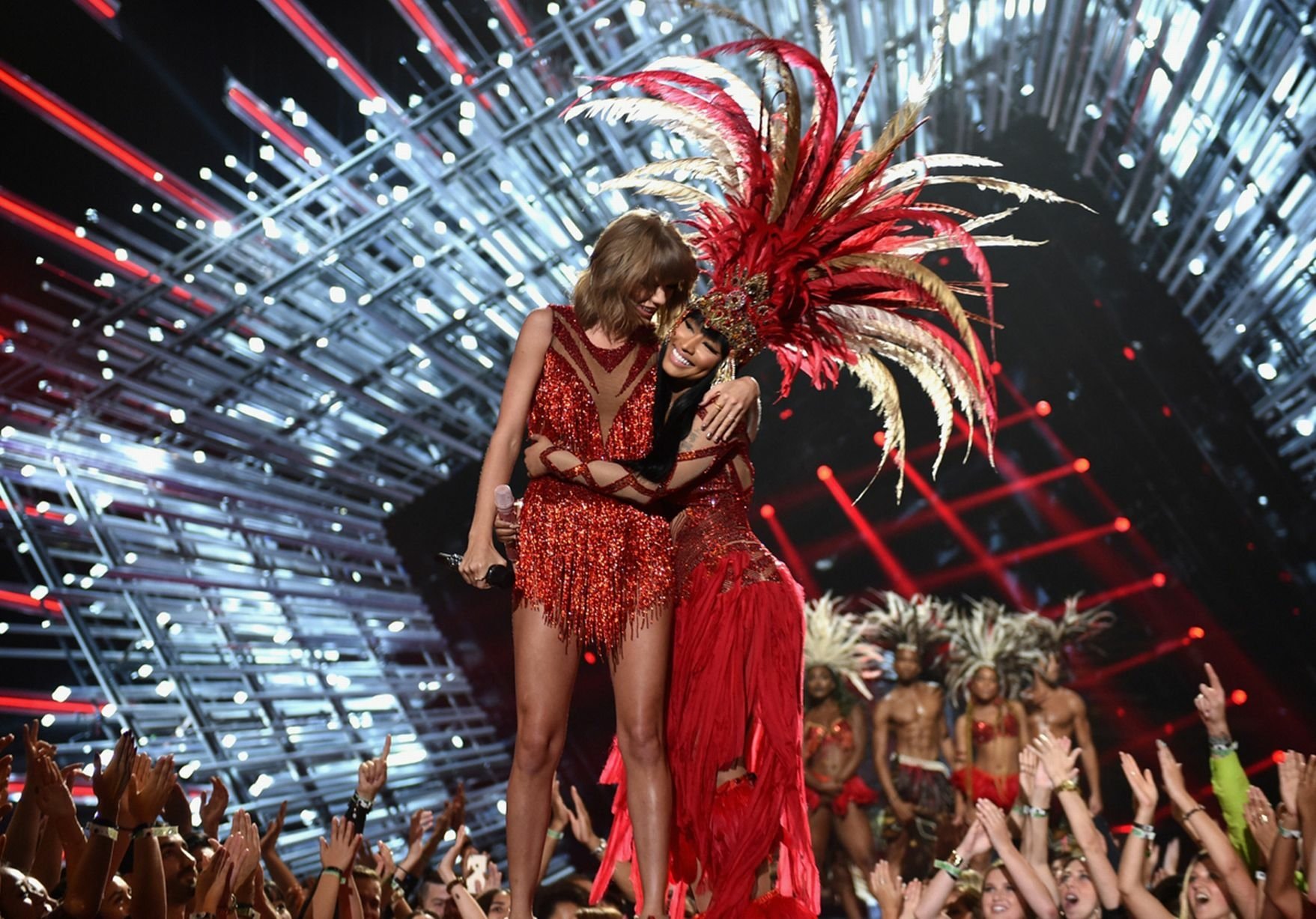 HD PC desktop wallpaper featuring Nicki Minaj and Taylor Swift performing together on stage with vibrant red costumes and an electrifying concert backdrop.