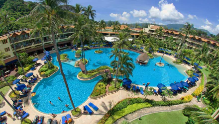 HD desktop wallpaper of a man-made resort pool surrounded by palm trees at a holiday resort in Phuket, Thailand, showcasing a tropical and relaxing atmosphere.