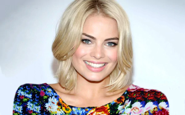 HD desktop wallpaper featuring Margot Robbie smiling confidently, dressed in a vibrant floral top, showcasing her stylish presence and captivating blue eyes.