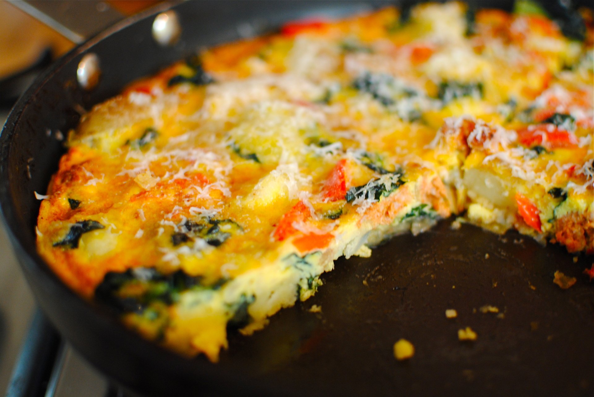 Close-up of a colorful frittata in a black skillet, showcasing vibrant vegetables and melted cheese, captured in 4K Ultra HD for a PC desktop wallpaper.
