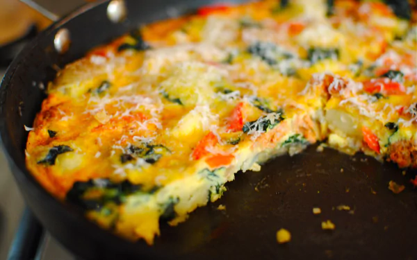 Close-up of a colorful frittata in a black skillet, showcasing vibrant vegetables and melted cheese, captured in 4K Ultra HD for a PC desktop wallpaper.