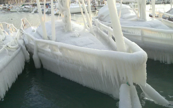 HD desktop wallpaper: winter photography of moored boats and dock coated in thick ice with long icicles hanging over dark harbor water.