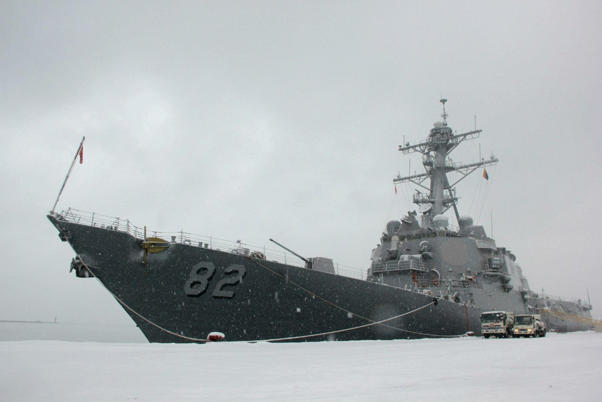 HD desktop wallpaper of military warship USS Lassen (DDG-82), a guided-missile destroyer, cutting through calm gray seas under an overcast sky.