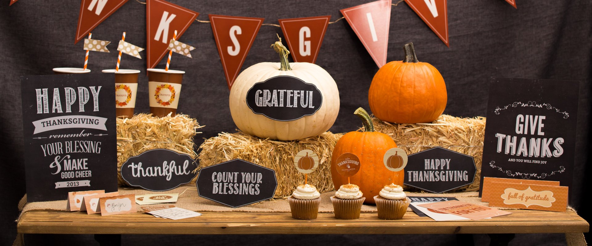 HD PC desktop wallpaper featuring Thanksgiving decorations with pumpkins, hay bales, cupcakes, and festive message signs expressing gratitude and holiday cheer.