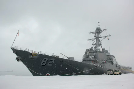 HD desktop wallpaper of military warship USS Lassen (DDG-82), a guided-missile destroyer, cutting through calm gray seas under an overcast sky.