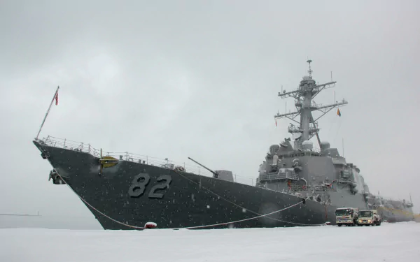 HD desktop wallpaper of military warship USS Lassen (DDG-82), a guided-missile destroyer, cutting through calm gray seas under an overcast sky.