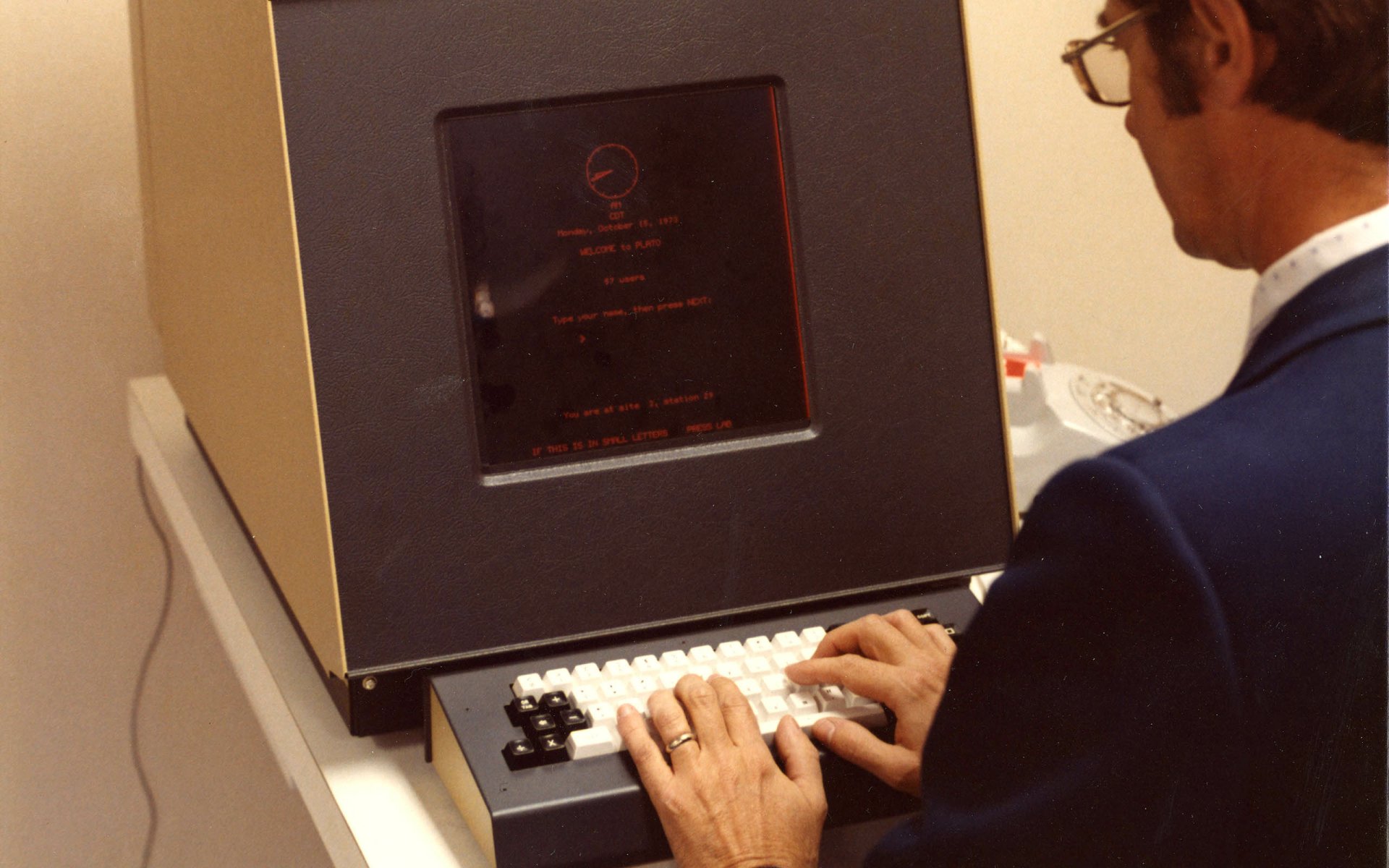 Vintage technology: person typing at an early computer terminal, rendered as a 2K Quad HD PC desktop wallpaper and background.