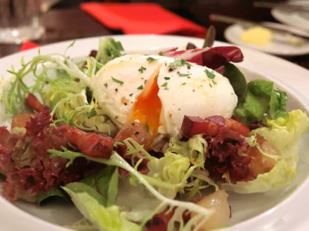 Close-up of a fresh Salade Lyonnaise with lettuce, crispy bacon, and a poached egg, captured in HD for a vibrant desktop wallpaper background.