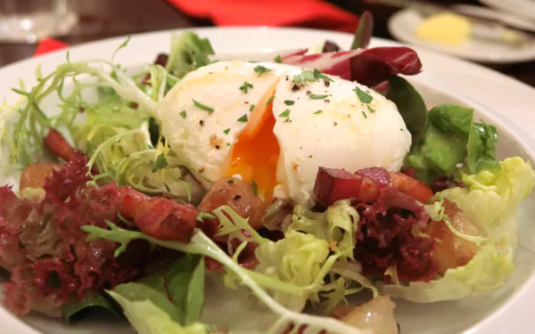Close-up of a fresh Salade Lyonnaise with lettuce, crispy bacon, and a poached egg, captured in HD for a vibrant desktop wallpaper background.