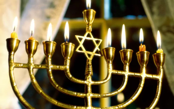 HD desktop wallpaper featuring a glowing Hanukkah menorah with nine lit candles and a Star of David centerpiece, celebrating the holiday's light and tradition.